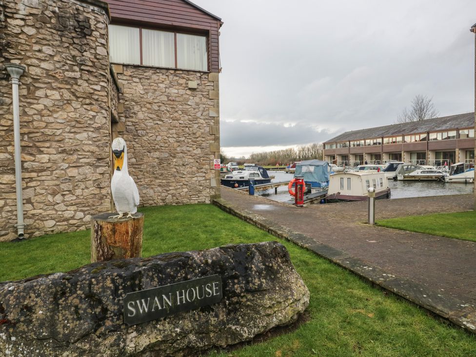 An outdoor area with a building, boats, and a swan statue at 6 Swan House in Tewitfield