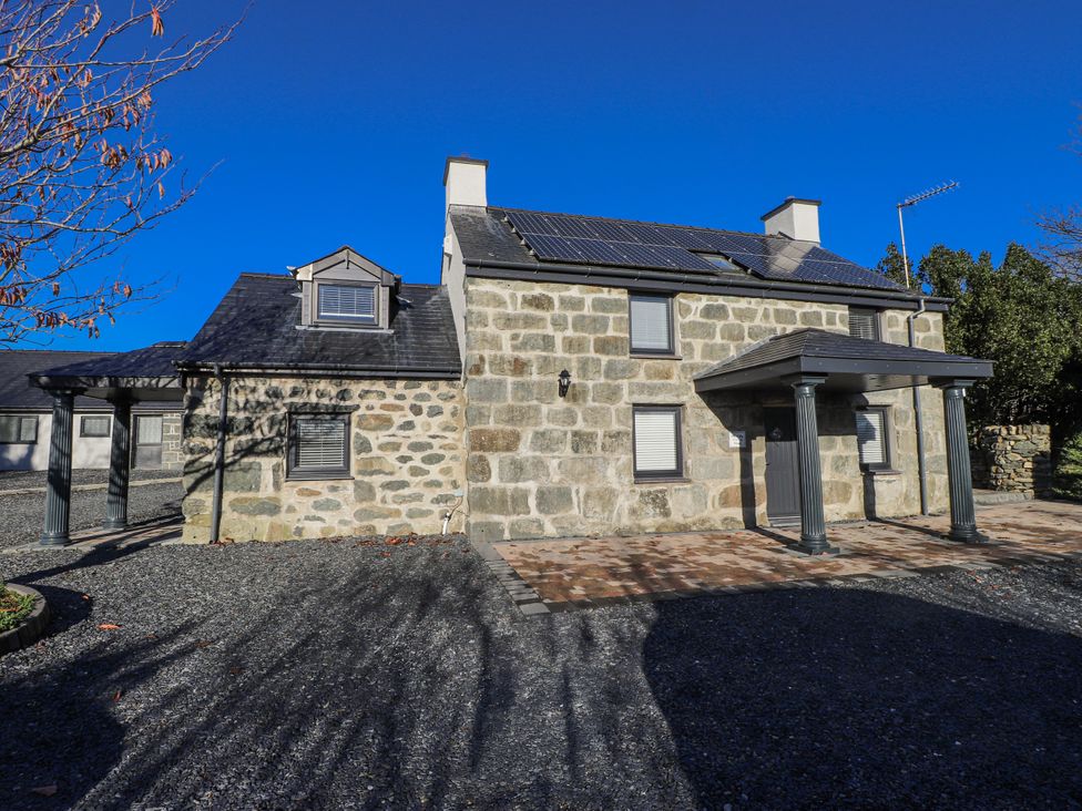 A building exterior with solar panels and gravel driveway at Ty'n Lon Pwllheli