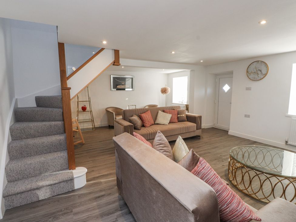 A living room with a staircase and sofa at Ty'n Lon in Pwllheli