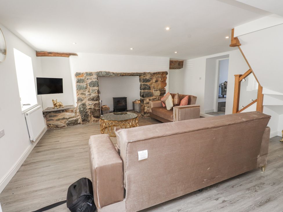 A living room with a sofa, coffee table, and television at Ty'n Lon Pwllheli