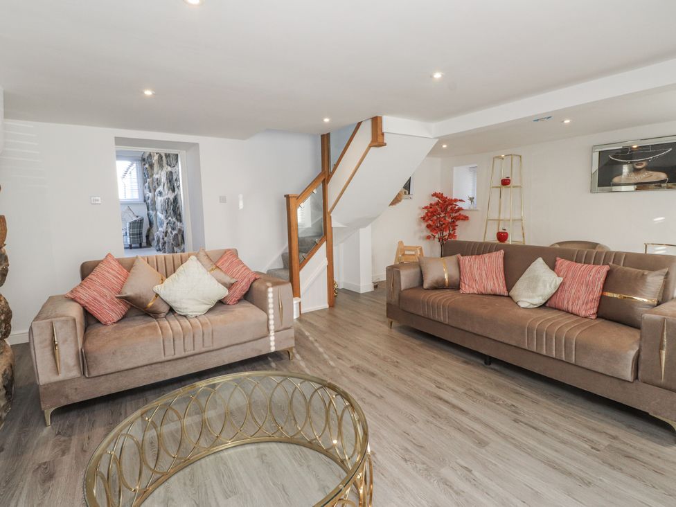 A living room with sofas and a staircase at Ty'n Lon in Pwllheli