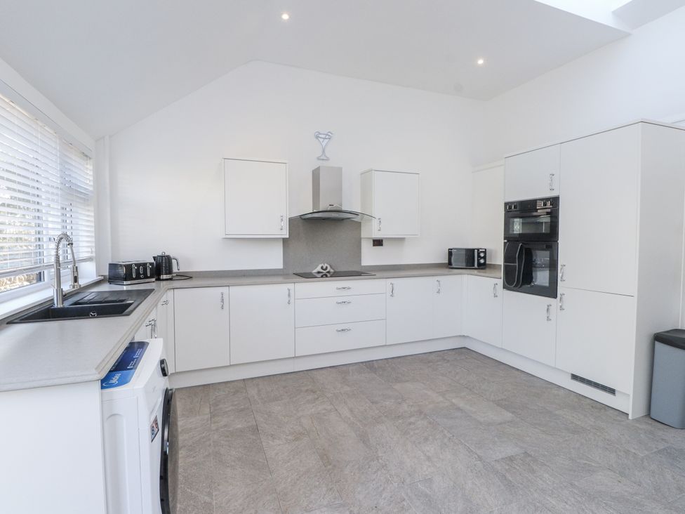 A kitchen with appliances and cabinets at Ty'n Lon in Pwllheli