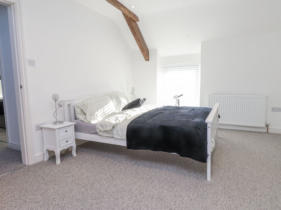 A bedroom with a bed and nightstand at Ty'n Lon Pwllheli