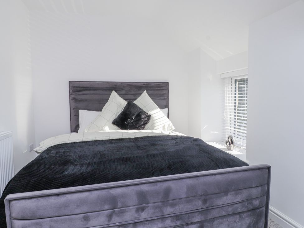 A bedroom with a bed and pillows at Ty'n Lon Pwllheli