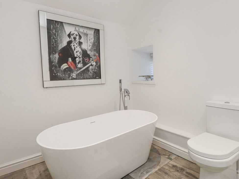 A bathroom with a bathtub and toilet at Ty'n Lon in Pwllheli