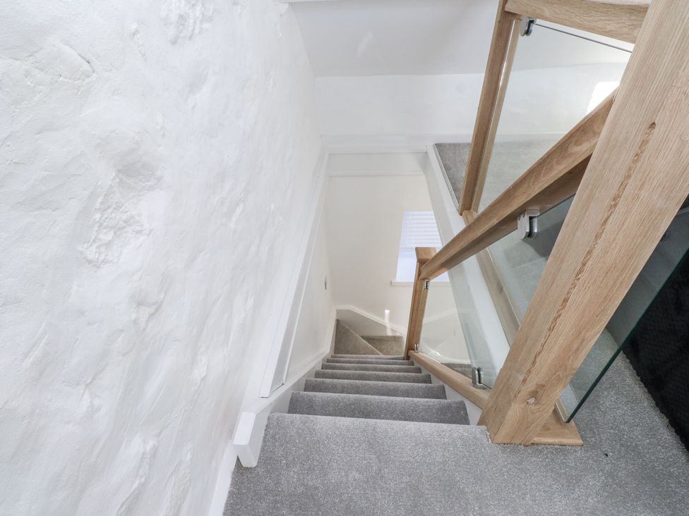 A staircase with a wooden handrail in Ty'n Lon Pwllheli