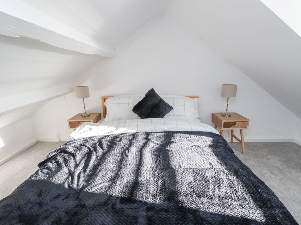 A bedroom with a bed and nightstands at Ty'n Lon in Pwllheli