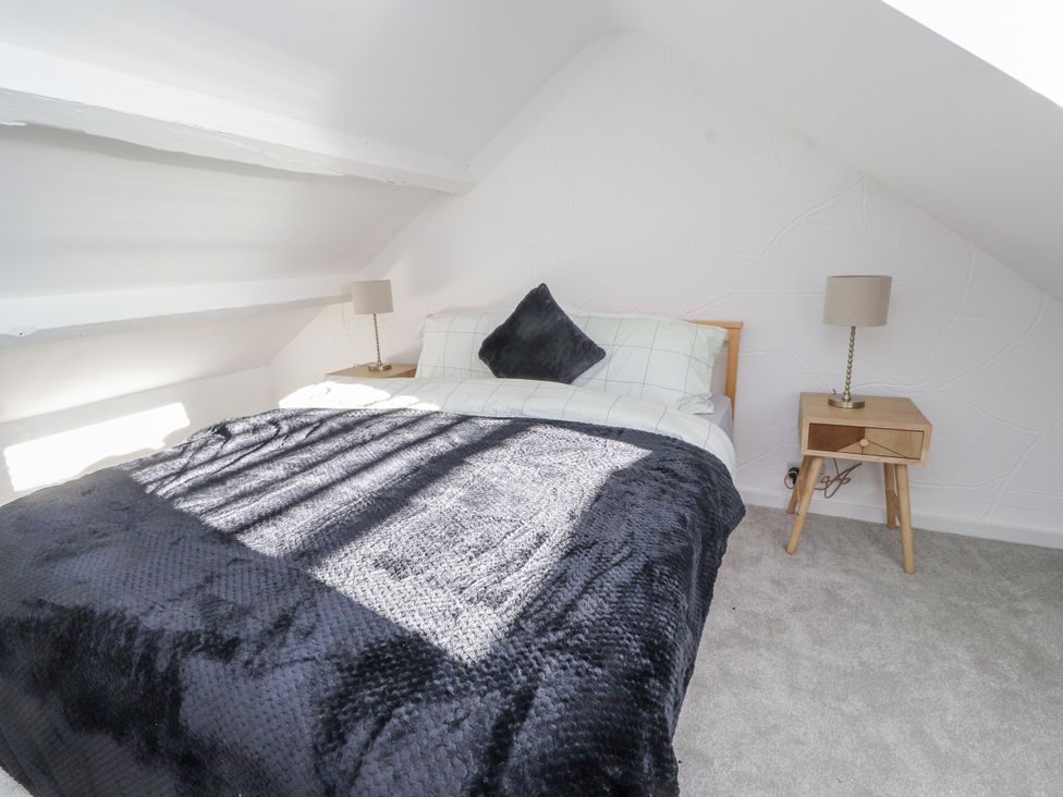 A bedroom with a bed and a bedside lamp at Ty'n Lon in Pwllheli