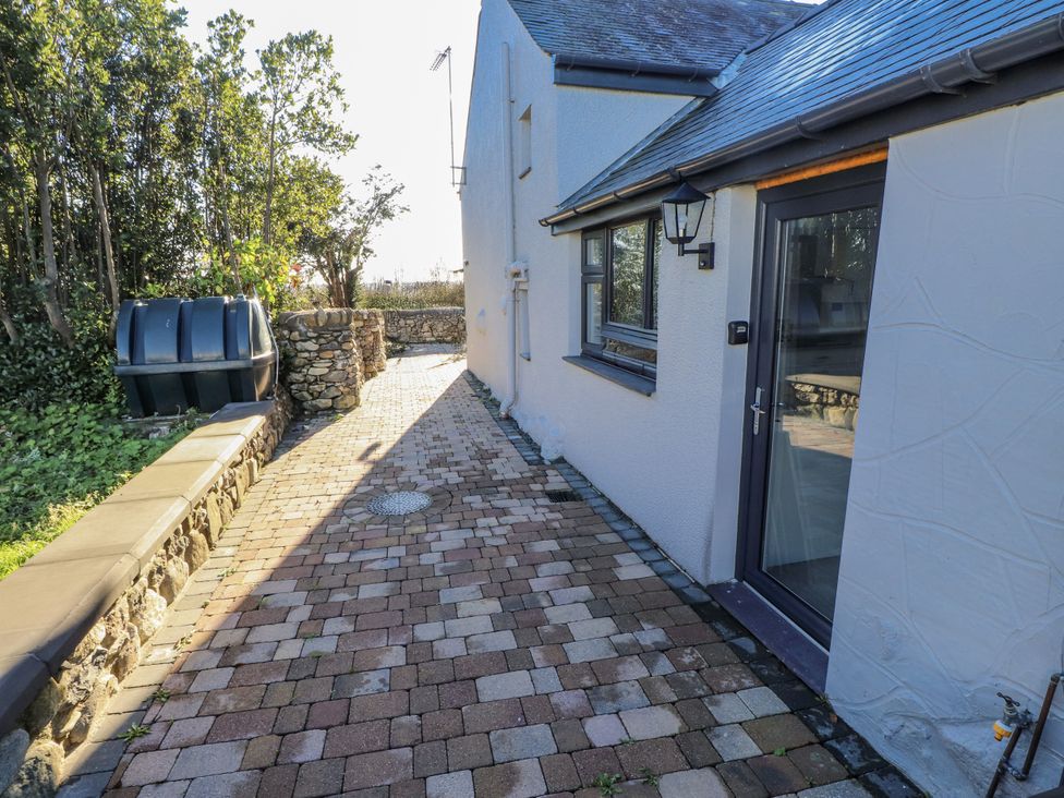 An outdoor pathway next to a house with a stone wall at Ty'n Lon Pwllheli