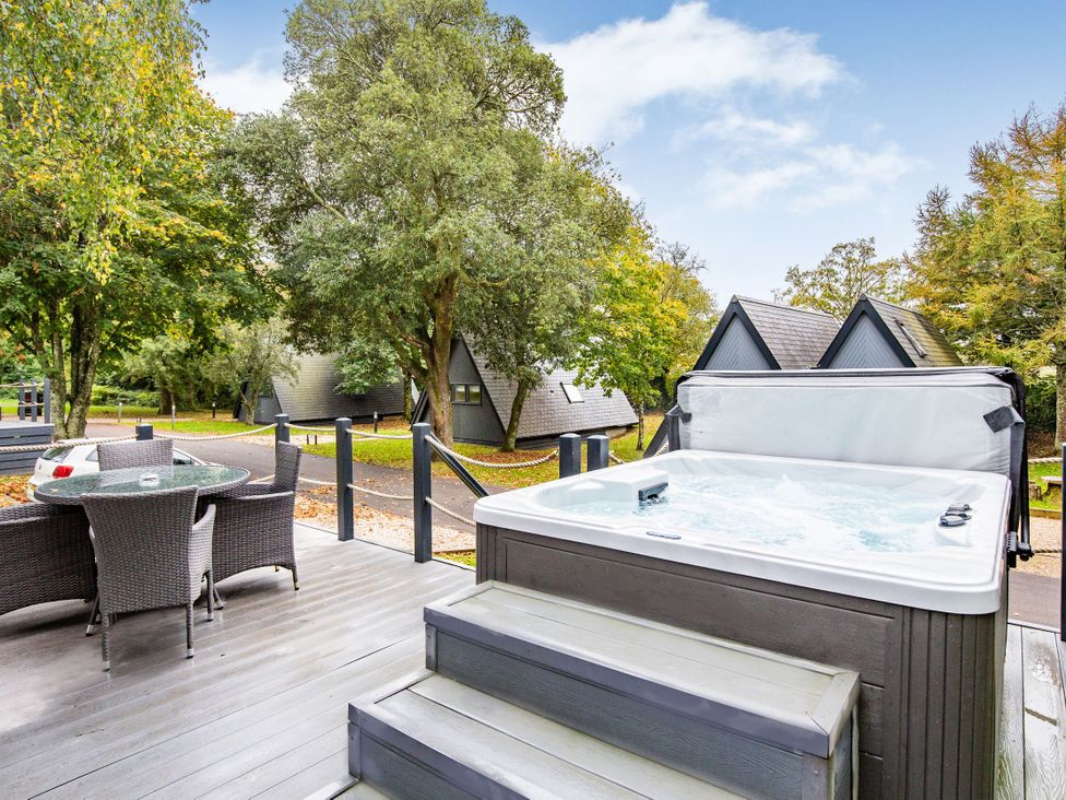 An outdoor area with a hot tub and seating at St Ives Studio Spa in Praze-An-Beeble