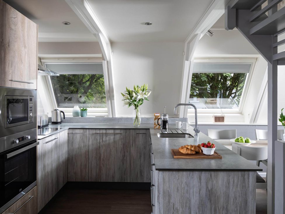 A kitchen with cabinets and a table with food at St Ives Lodge 2 Spa Praze-An-Beeble