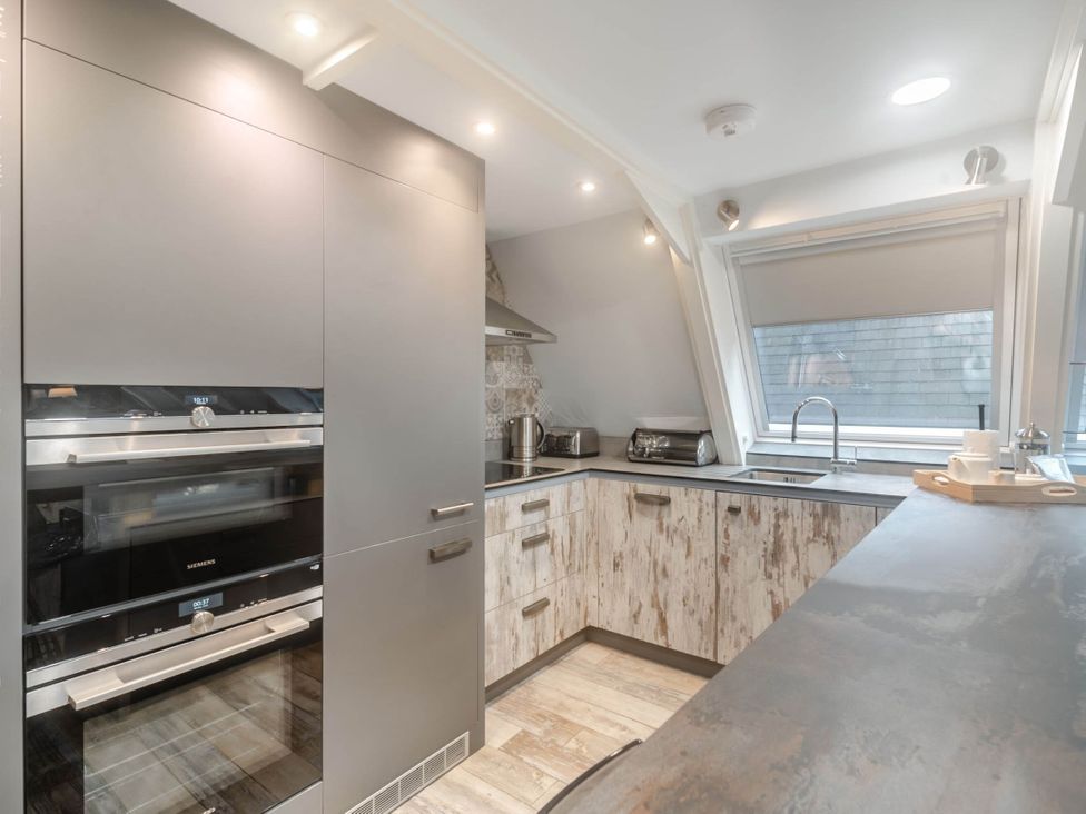 A kitchen with appliances and cabinets at Glass Lodge in Praze-An-Beeble