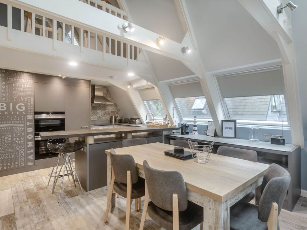 A kitchen with a dining table and bar stools at Glass Lodge in Praze-An-Beeble
