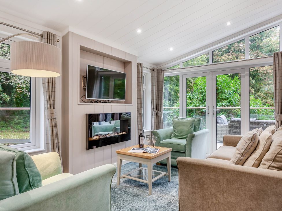 A living room with a television and seating at Aubyn Lodge Spa in Praze-An-Beeble