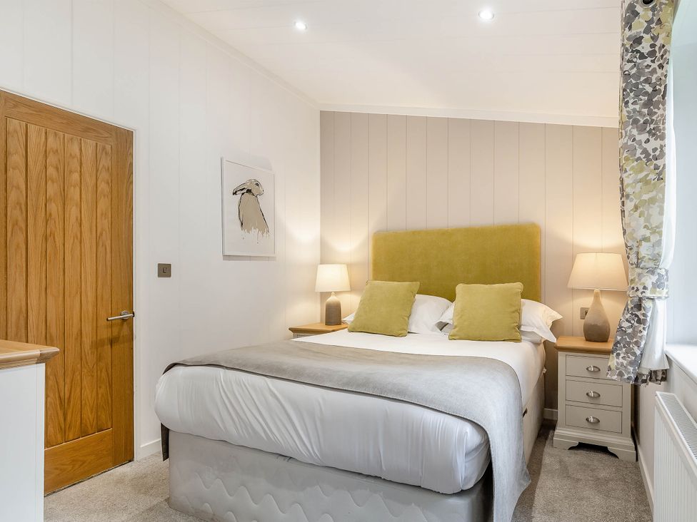 A bedroom with a bed and nightstands at Aubyn Lodge Spa in Praze-An-Beeble