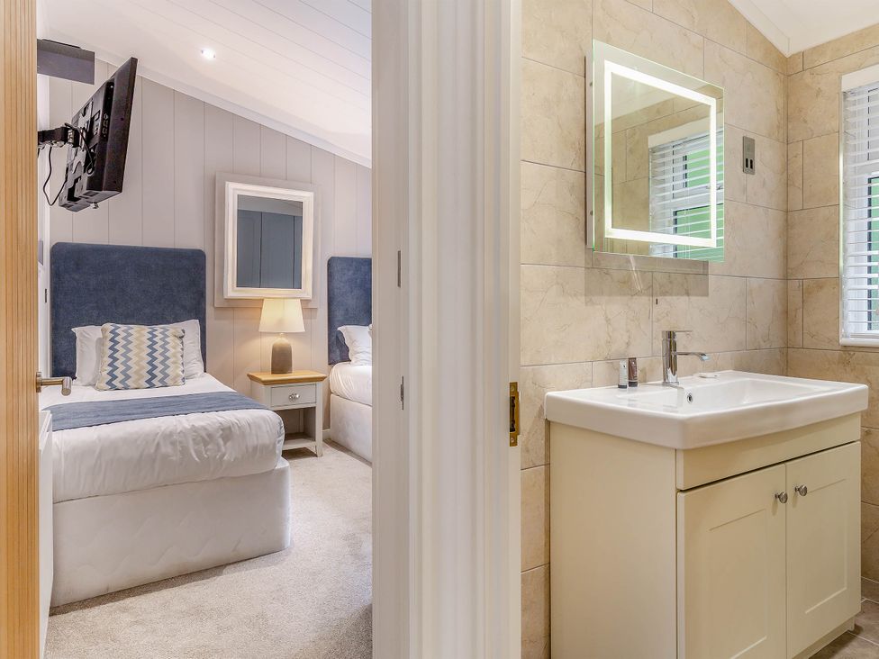 A bedroom with two beds and a bathroom area at Aubyn Lodge Spa Praze-An-Beeble