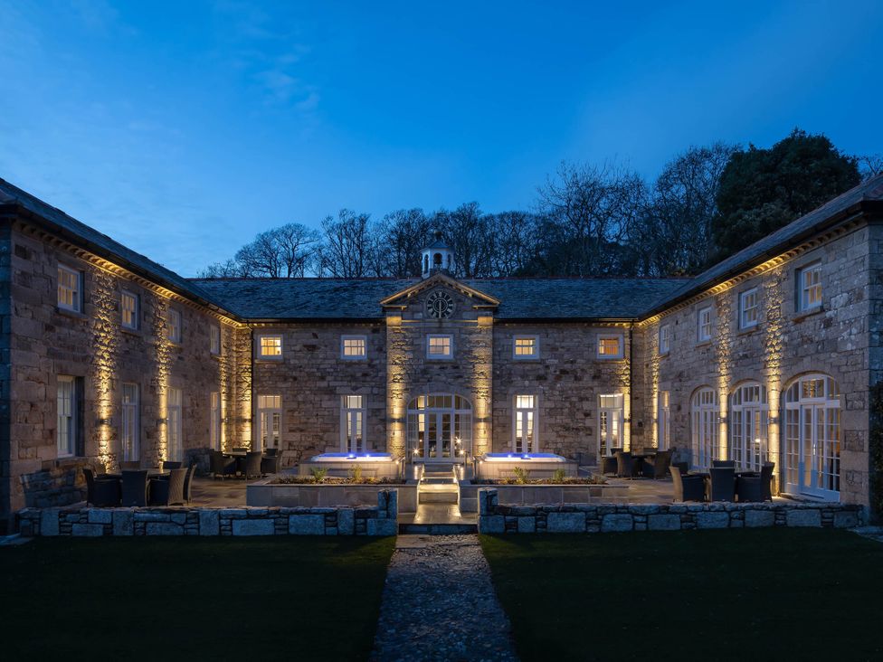 An exterior view of a stone building with patio and lights at Coach House Praze-An-Beeble