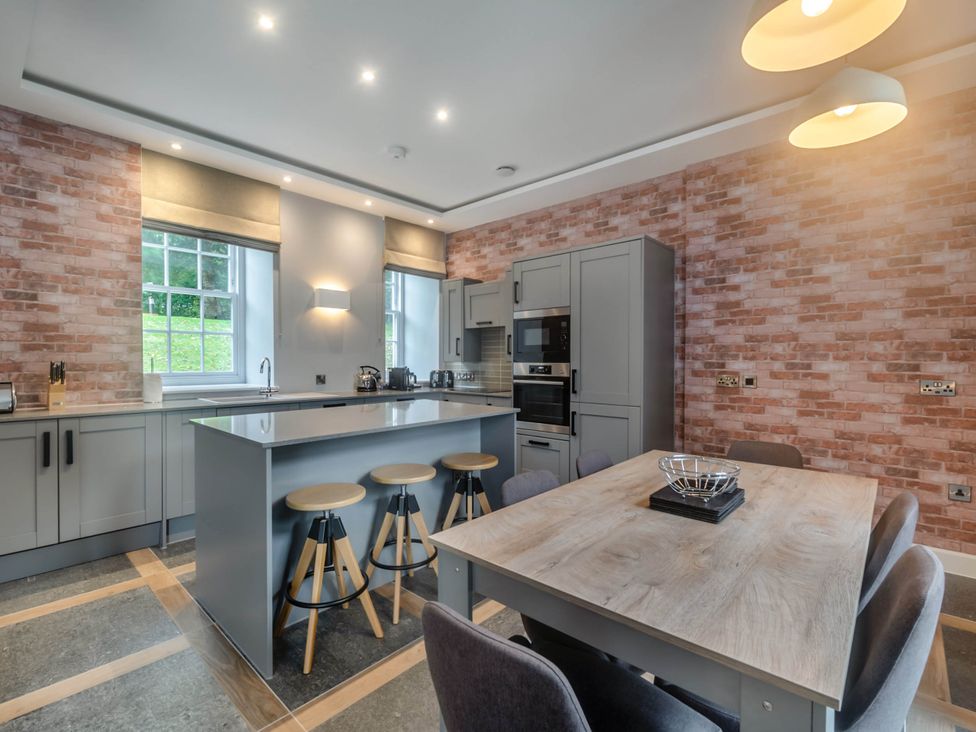 A kitchen with an island and stools at Coach House in Praze-An-Beeble