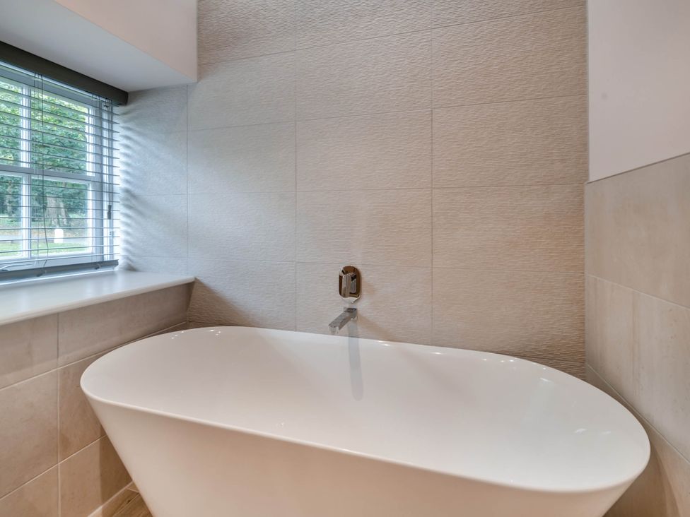 A bathroom with a bathtub and a window at Coach House in Praze-An-Beeble