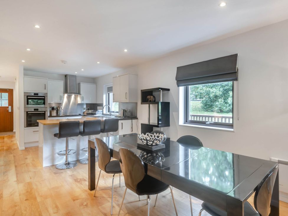 A kitchen with a dining table and bar stools at Cornwall Lodge Spa in Praze-An-Beeble