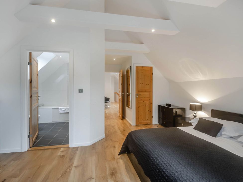 A bedroom with bed, nightstand, and an en-suite bathroom at Cornwall Lodge Spa in Praze-An-Beeble