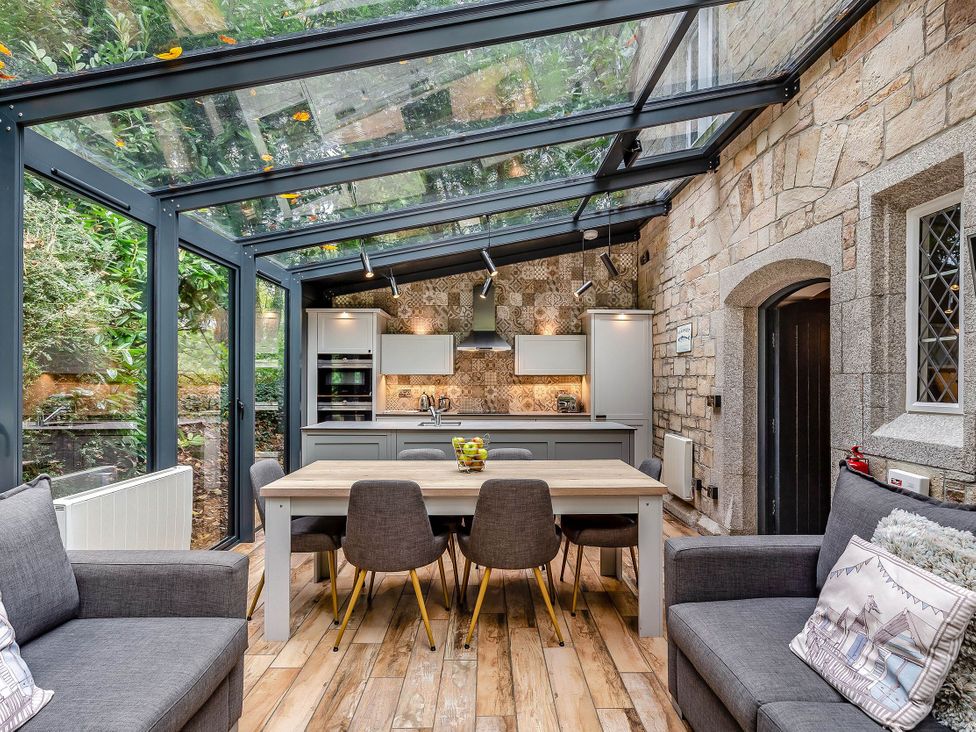 A kitchen with a dining table and chairs in a conservatory at The Gatehouse Praze-An-Beeble