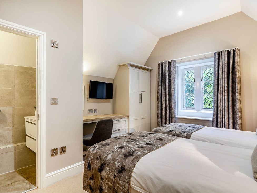 A bedroom with twin beds and a desk at The Gatehouse in Praze-An-Beeble