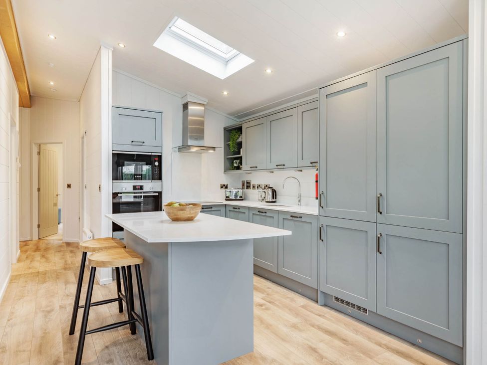 A kitchen with a central counter and stools at Lake View Spa in Praze-An-Beeble
