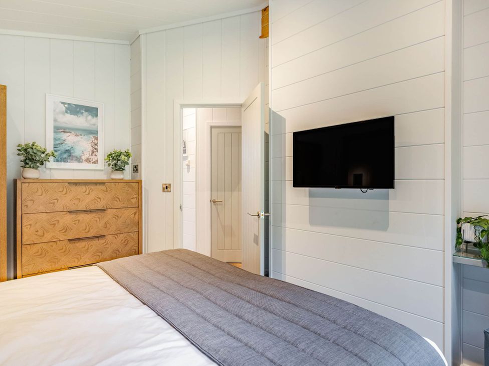 A bedroom with a bed and a television mounted on the wall at Lake View Spa in Praze-An-Beeble