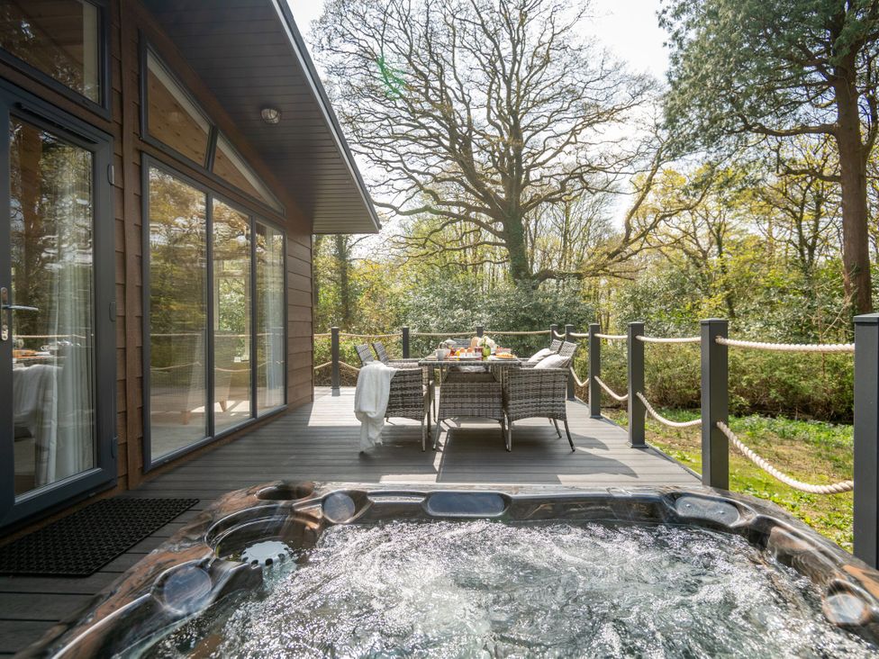 An outdoor area with a hot tub and dining table at Argel Spa Pet in Praze-An-Beeble