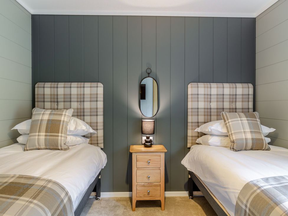 A bedroom with two beds and a bedside table at Argel Spa Pet in Praze-An-Beeble