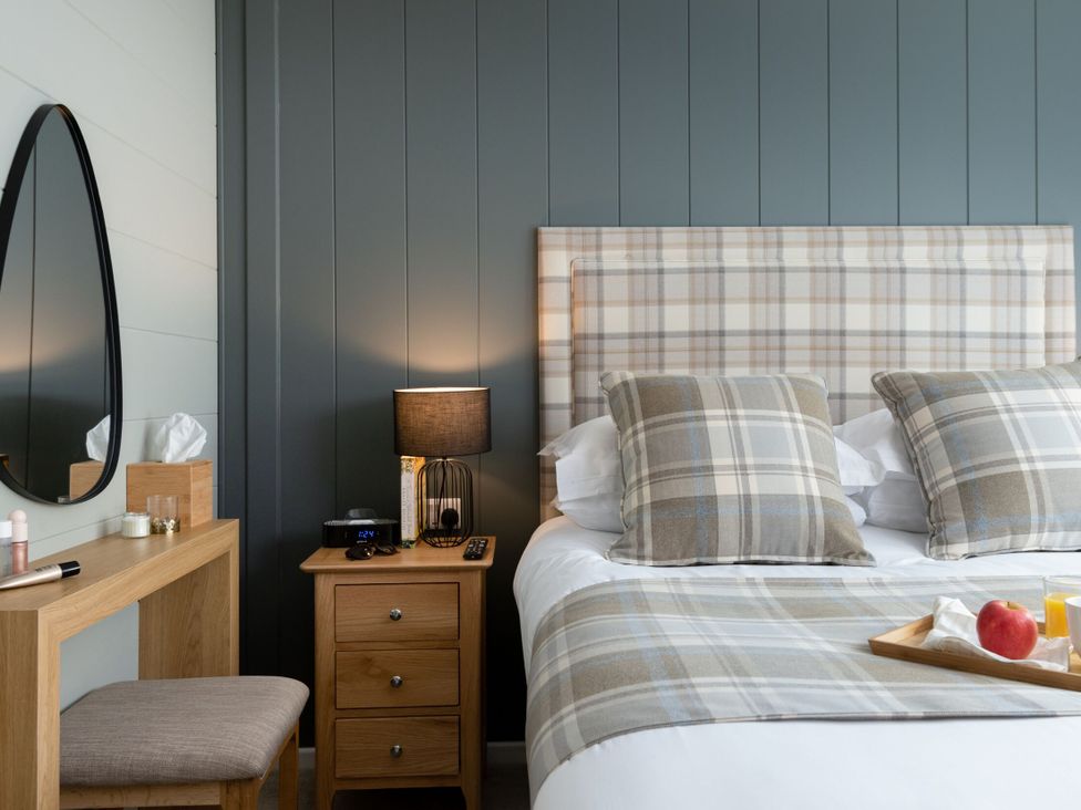 A bedroom with a bed, bedside table, and mirror at Argel Spa Pet in Praze-An-Beeble