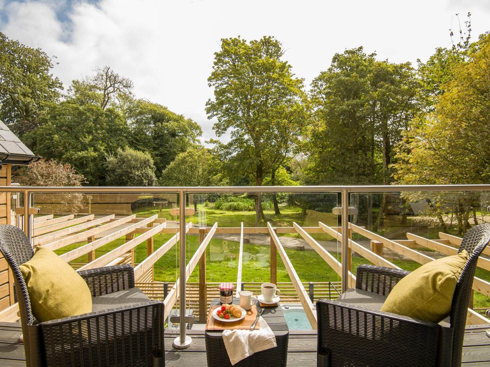 A balcony with chairs and a table overlooking a garden at Kilden Pet in Praze-An-Beeble