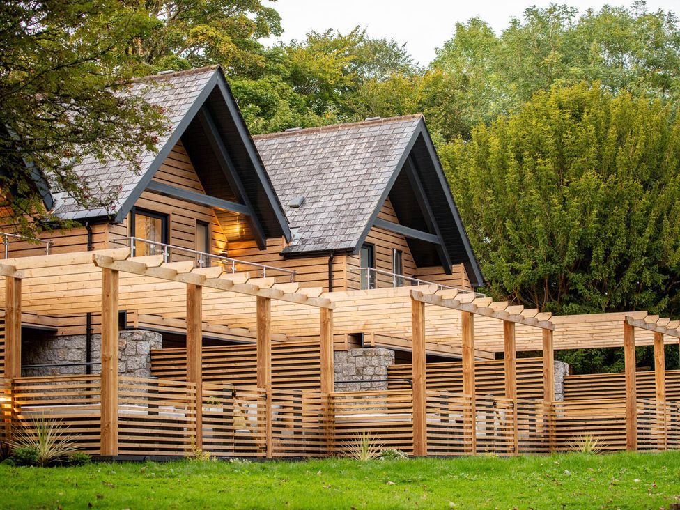A wooden house with a balcony and pergola at Kilden Pet in Praze-An-Beeble