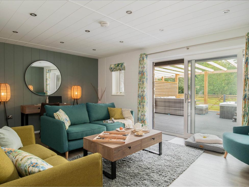A living room with sofas and doors leading to a patio at Kilden Pet in Praze-An-Beeble