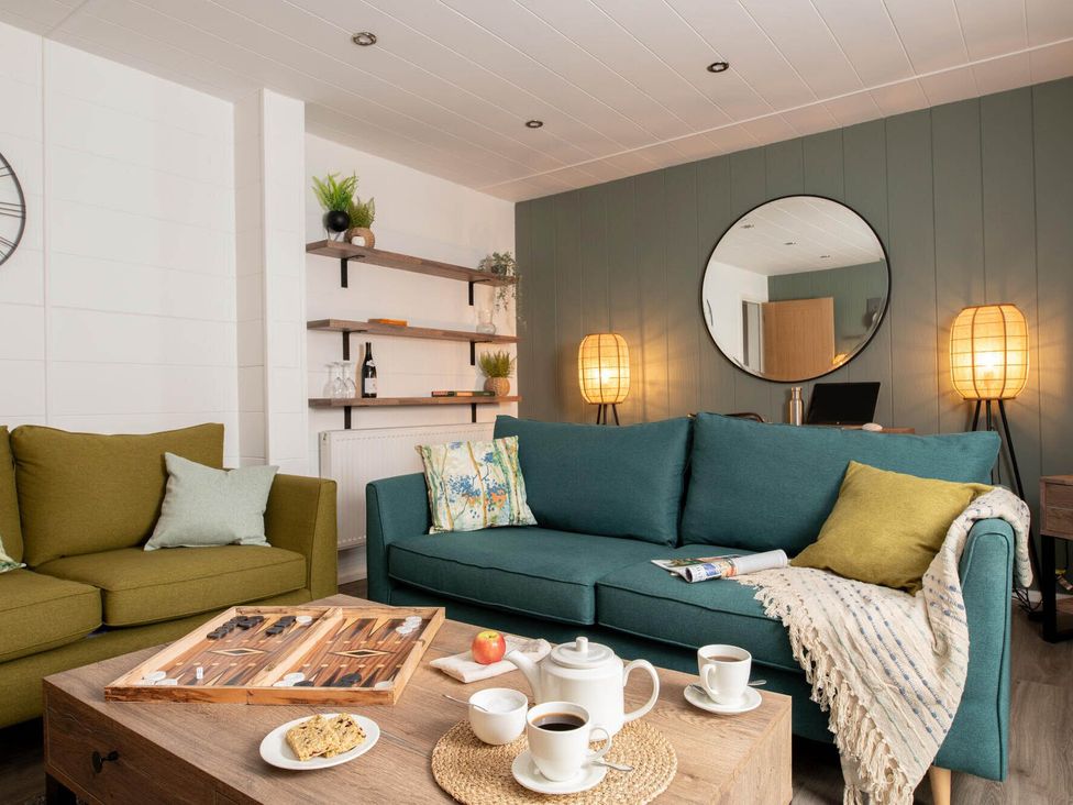 A living room with a sofa, coffee table, and decorative elements at Kilden Pet in Praze-An-Beeble