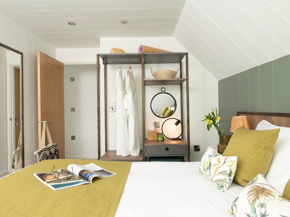 A bedroom with a bed and shelf containing decorative items at Kilden Pet in Praze-An-Beeble