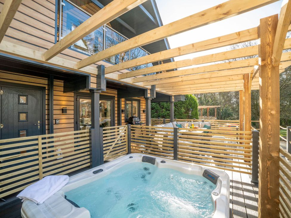 An outdoor area with a hot tub and dining set at Lowarth Lodge Spa Pet Praze-An-Beeble