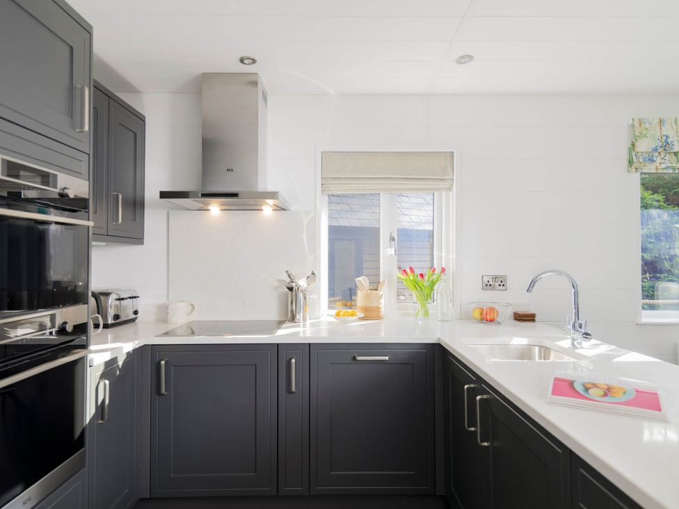 A kitchen with appliances and a window at Lowarth Lodge Spa Pet Praze-An-Beeble
