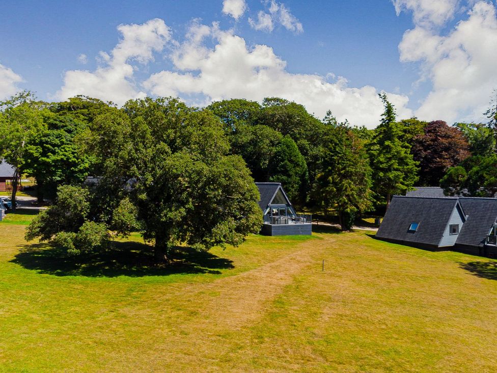 A grassy area with trees and cabins at Lowarth Lodge Spa Pet in Praze-An-Beeble