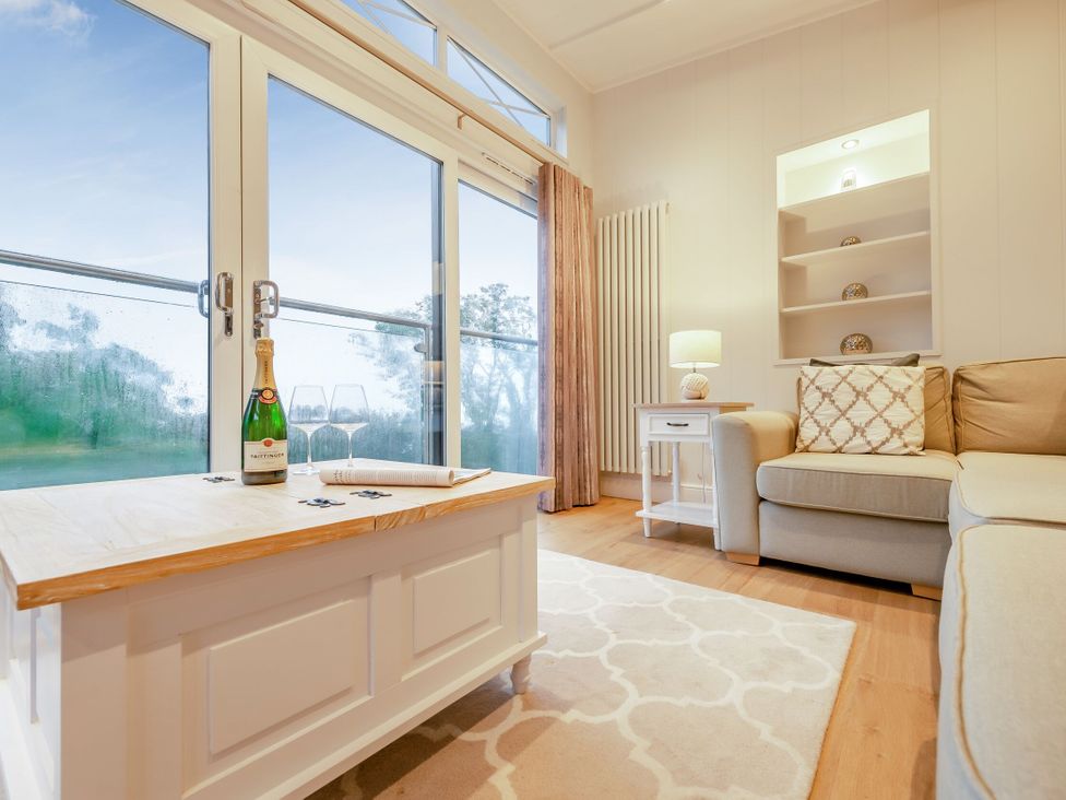 A living room with a coffee table and champagne on display at Milk Wood 2 in Laugharne