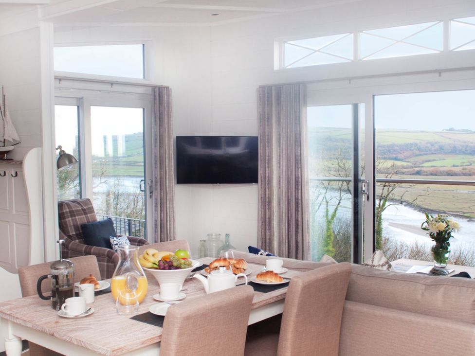A living room with a dining table and view of the river at Milk Wood 2 Spa in Laugharne
