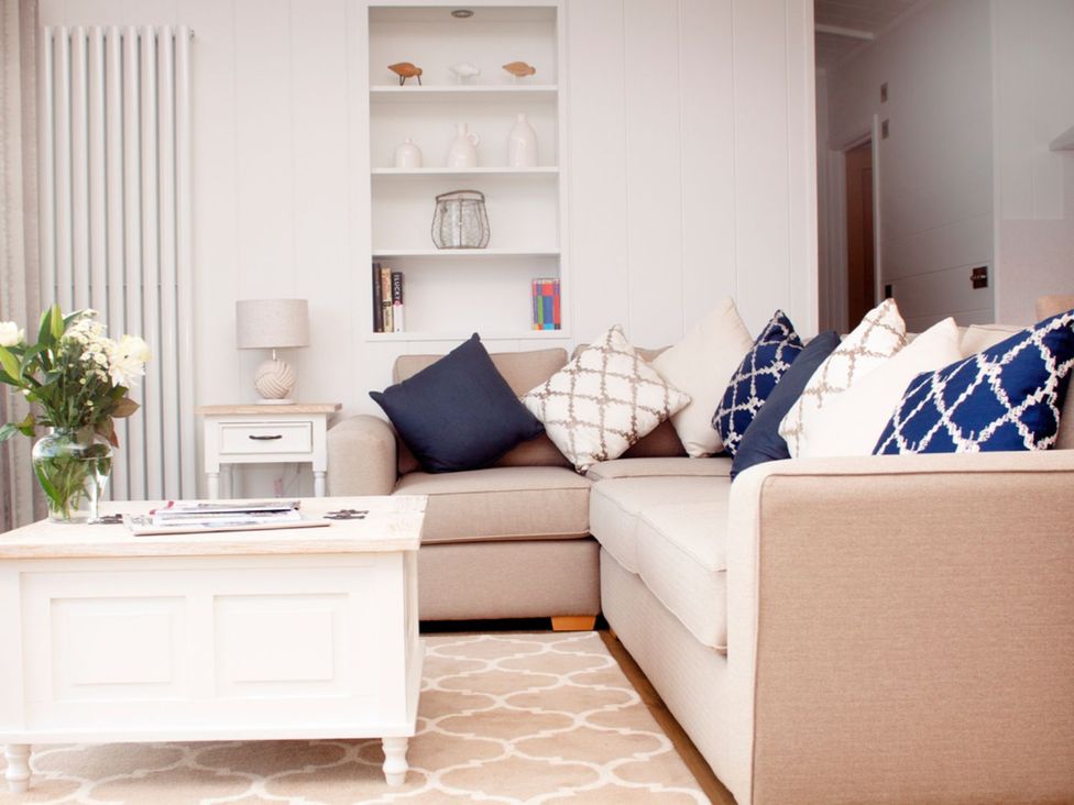 A living room with a sofa, coffee table, and lamp at Milk Wood 2 Spa in Laugharne
