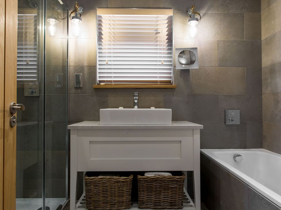 A bathroom with a vanity and sink next to a bathtub at Dylan Spa in Laugharne