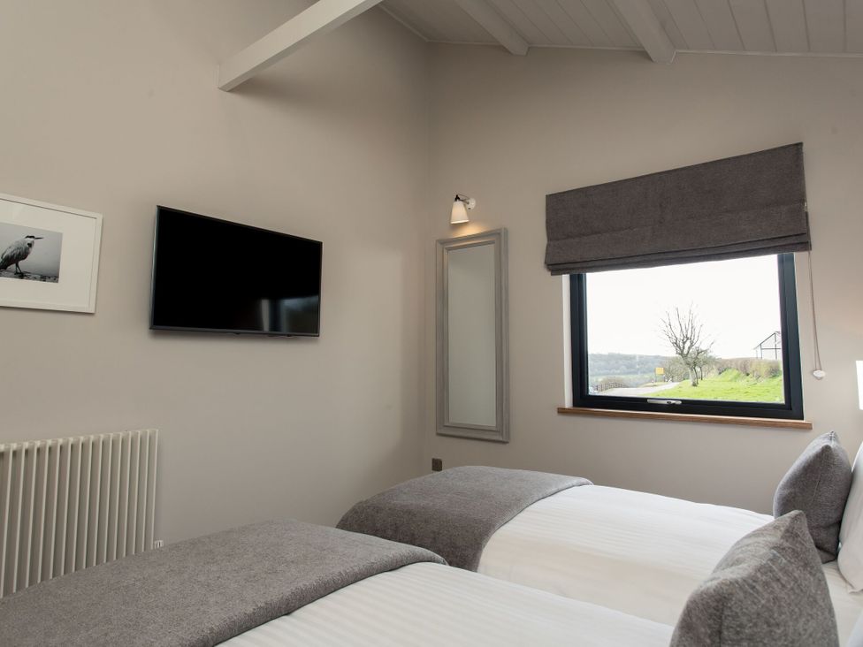 A bedroom with two beds and a television at Dylan Spa Laugharne