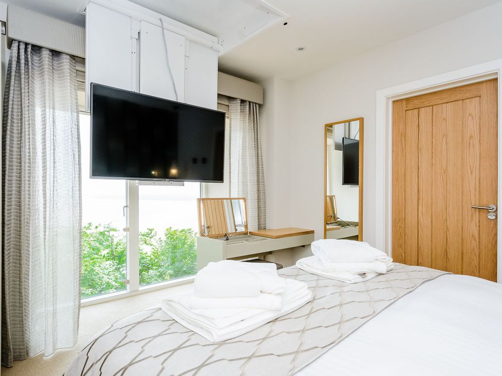 A bedroom with a bed, television, and mirror at The View in Laugharne