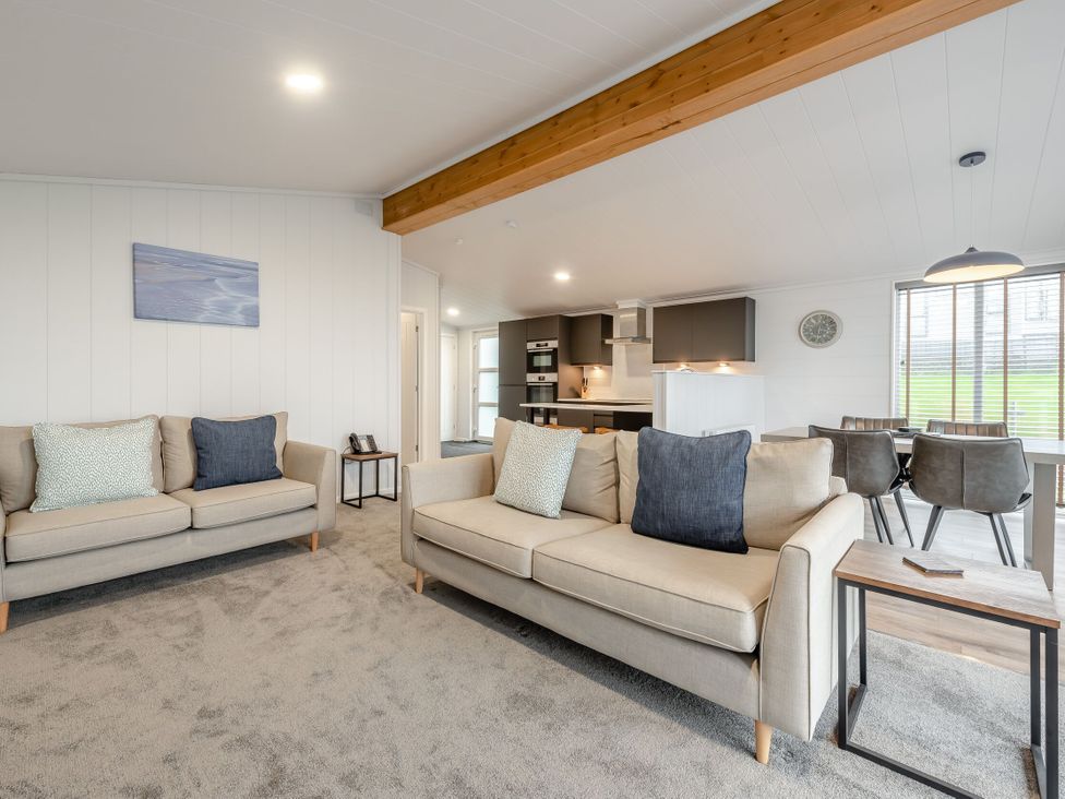 A living room with sofas and a dining area at Sonnet 2 Spa Laugharne