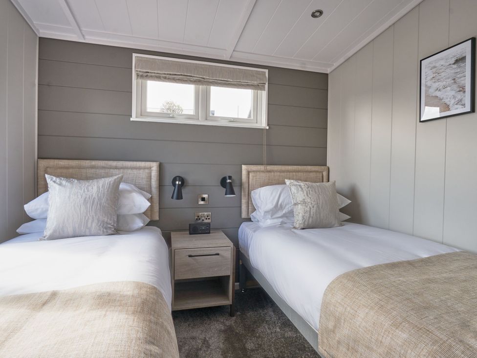 A bedroom with twin beds and a nightstand at Milk Wood 3 in Laugharne