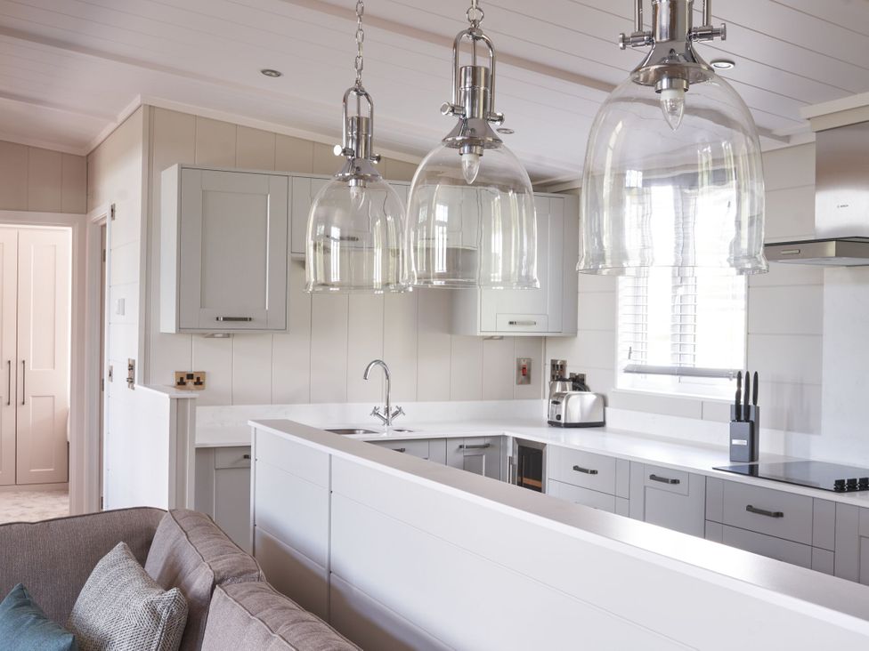 A kitchen with gray cabinets and pendant lights at Milk Wood 3 Spa in Laugharne