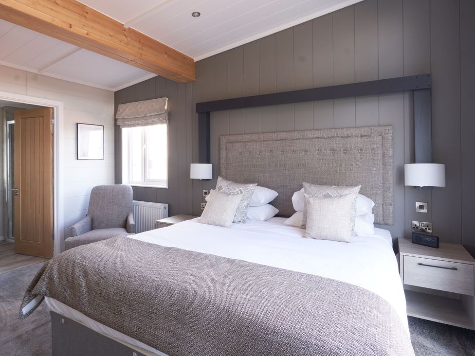 A bedroom with a bed and chair at Milk Wood 3 Spa in Laugharne